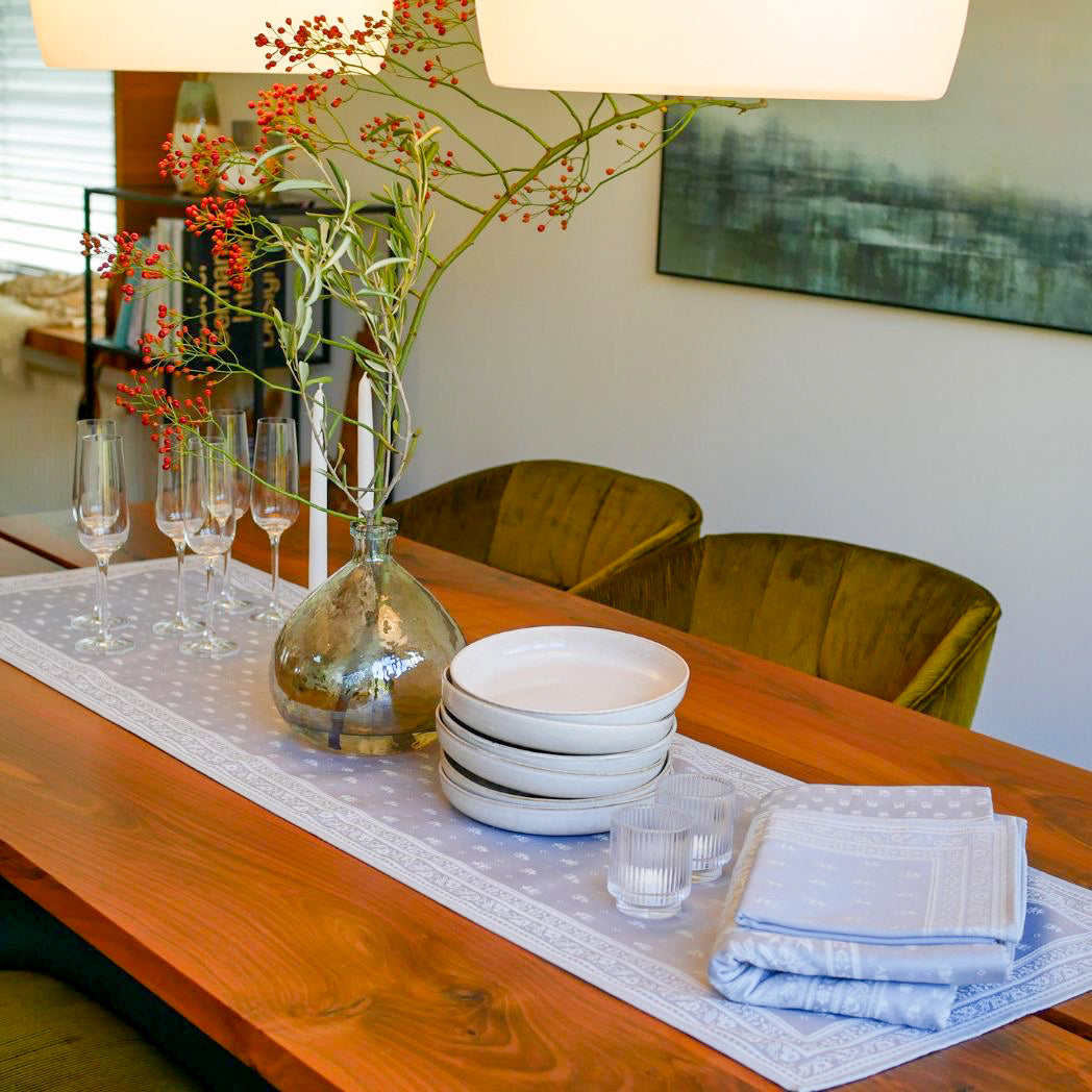 Ein hochwertiger Tischläufer aus hellgrauem Jacquard-Stoff mit Fleckschutz für eine sorgfältige tägliche Verwendung.