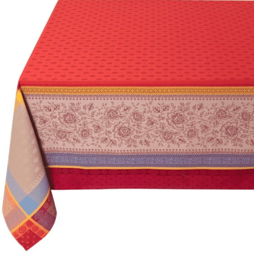 Jacquard‑Tischdecke in intensivem Rot mit beigefarbenen Mustern und dekorativen blauen Akzenten auf einem Esstisch.